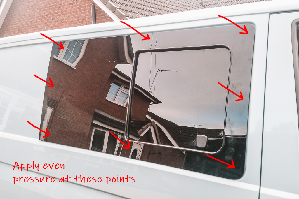 Labelled picture showing where to apply pressure on a bonded campervan window when it's first put into place.