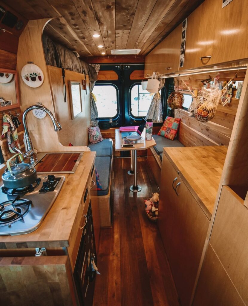 A kitchen, a removable table and two bench seats in a camper van conversion