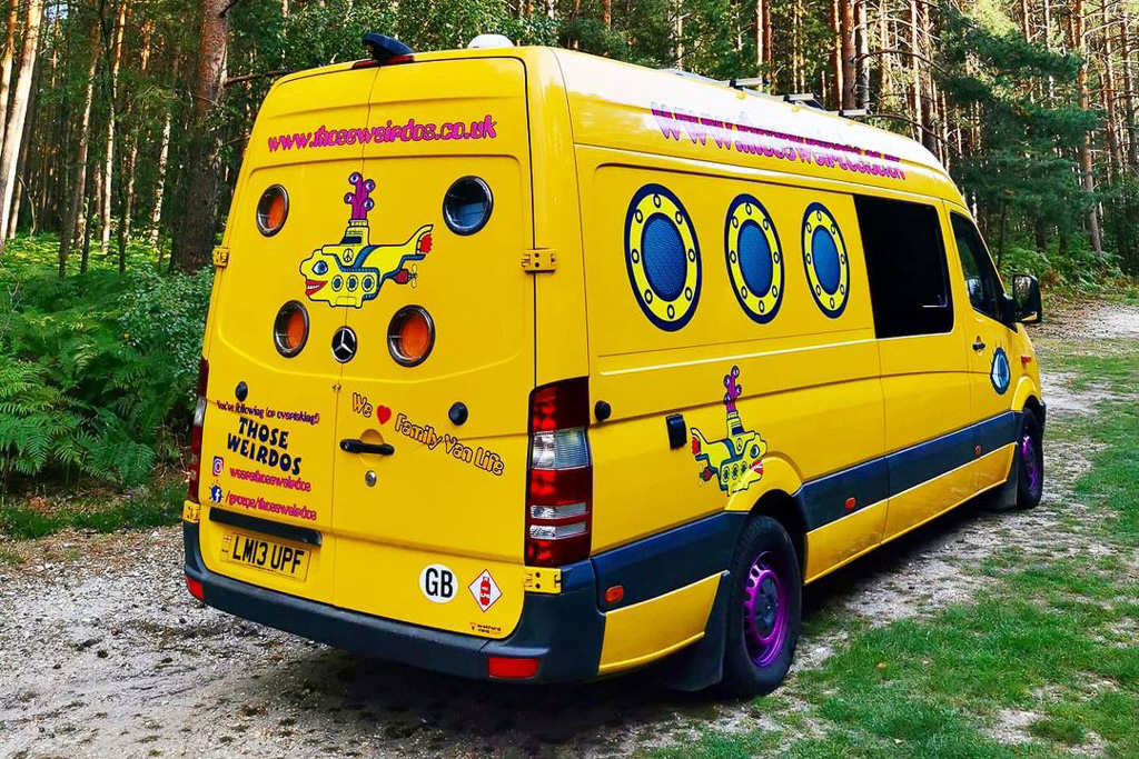 A Mercedes Spriner camper van painted like the yellow submarine with porthole windows in the rear doors