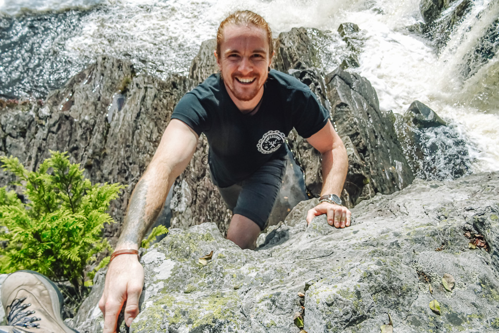 More about Jolly: climbing a rockface with a waterfall behind him.
