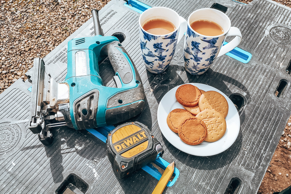 Hand tools with cups of tea and biscuits in preparation for fitting a camper van window