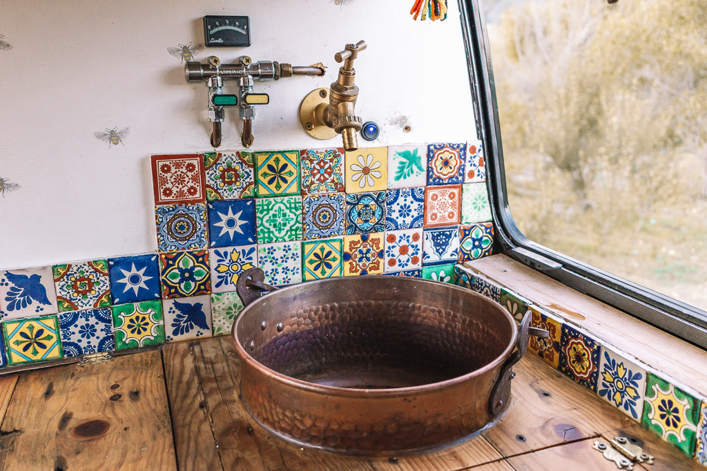 An upcycled copper jam pot as an integrated sink in a campervan kitchen