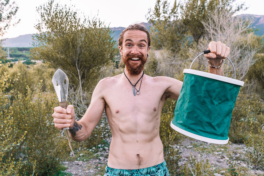 Man holding a collapsible bucket that's used for a toilet in a campervan conversion