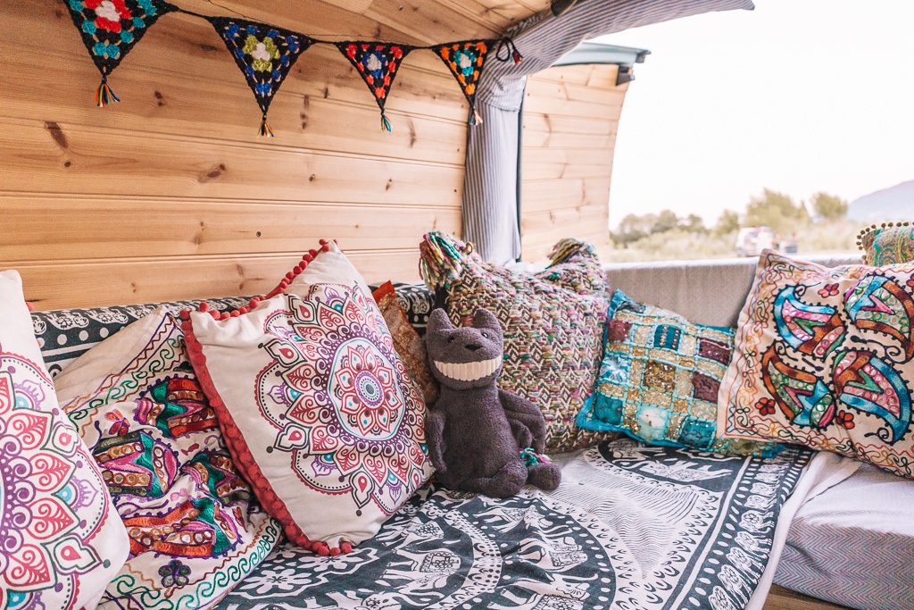 Cusions, a smiling teddy bear and bunting in a DIY campervan conversion