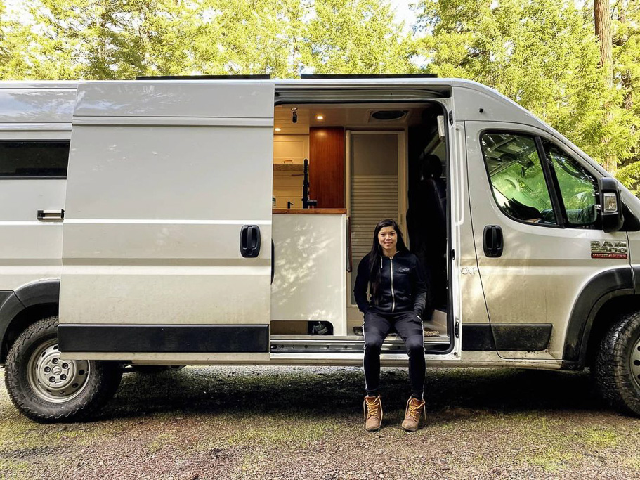A lady sa in the doorway of her converted campervan