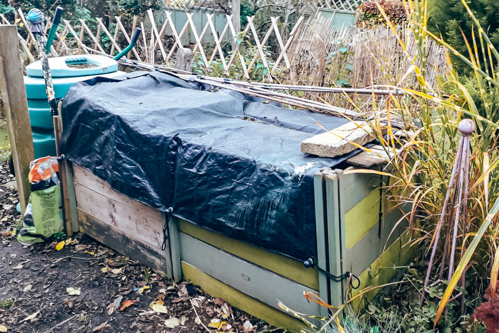 Two wooden compost heaps covered over with black tarp