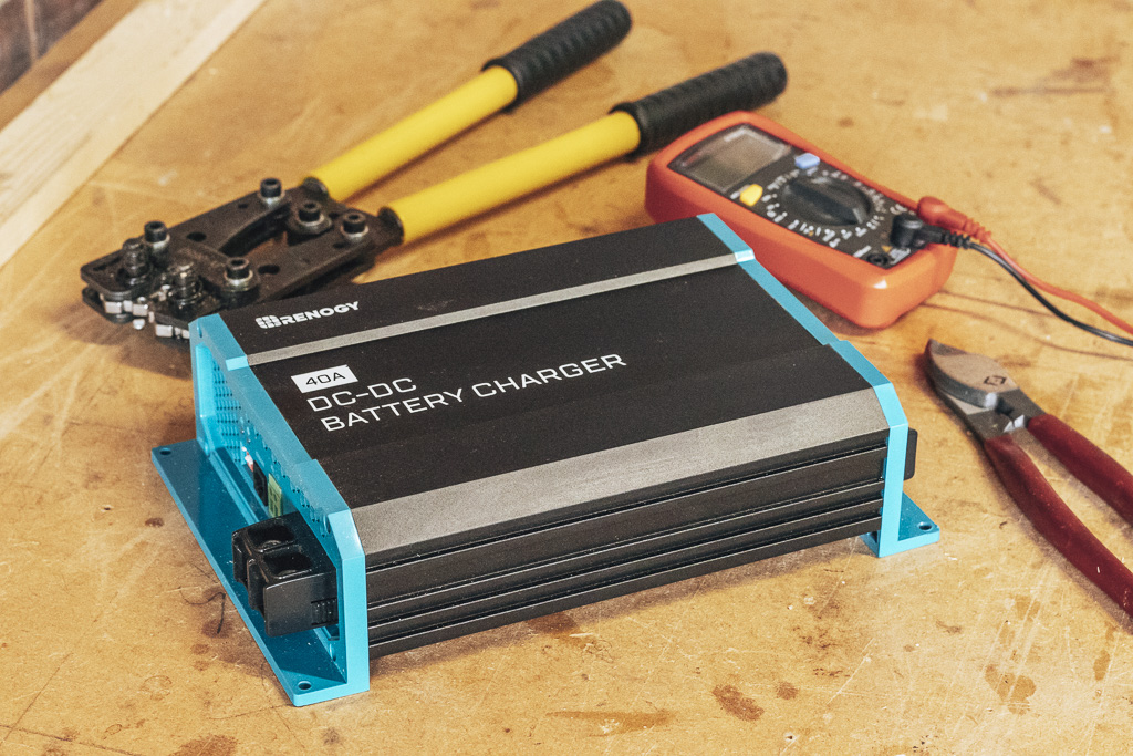 Renogy 40A DC-DC battery charger on a table with a cable crimper, digital multimeter and wire cutters