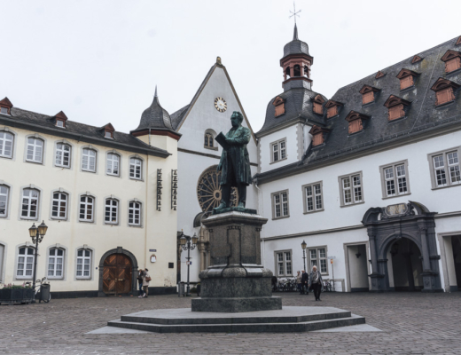 A statue of a man in a town square with white buildings