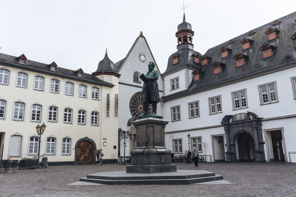 A statue of a man in a town square with white buildings