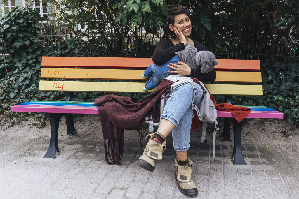 Nemi breastfeeding on a rainbow coloured bench