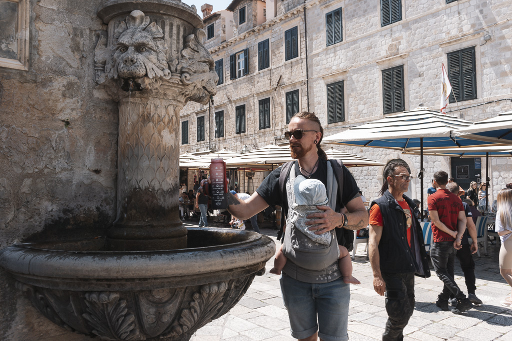 A man filling his water bottle from a public water fountain in Croatia