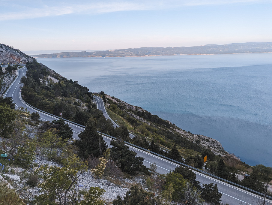 A coastal road in Croatia with a very blue sea and lots of green vegetation